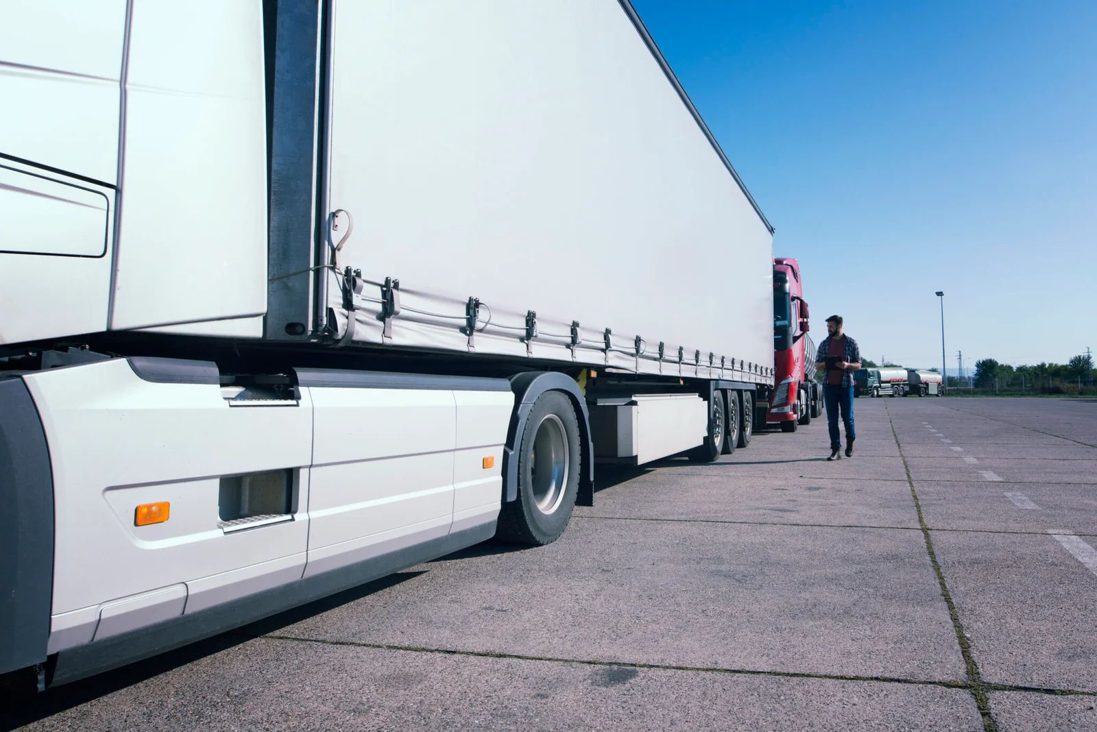 HGV driver walking alongside a lorry in a transport yard