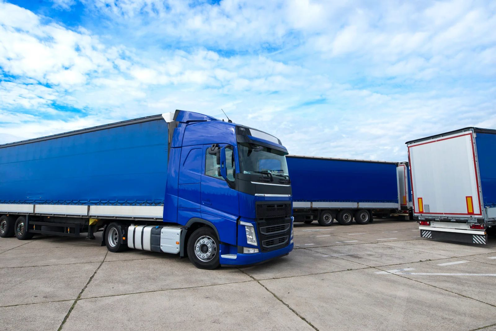 Blue HGV lorry parked in a transport yard with blue sky