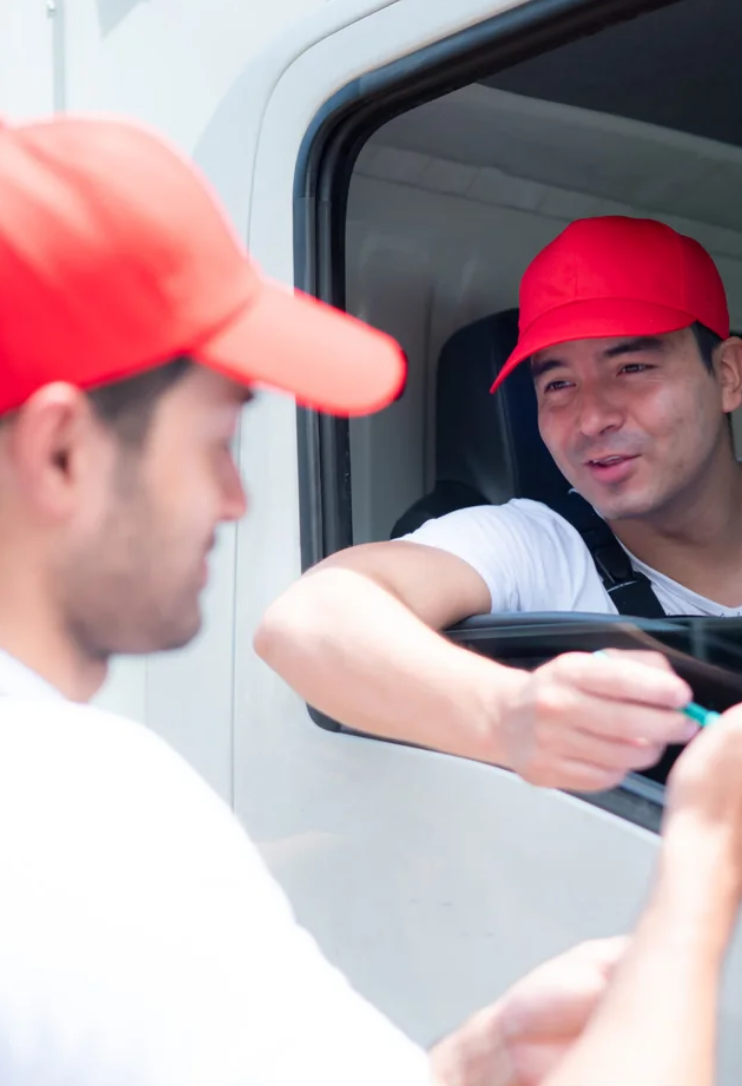 Two DR Transport drivers in red caps inside a truck cab